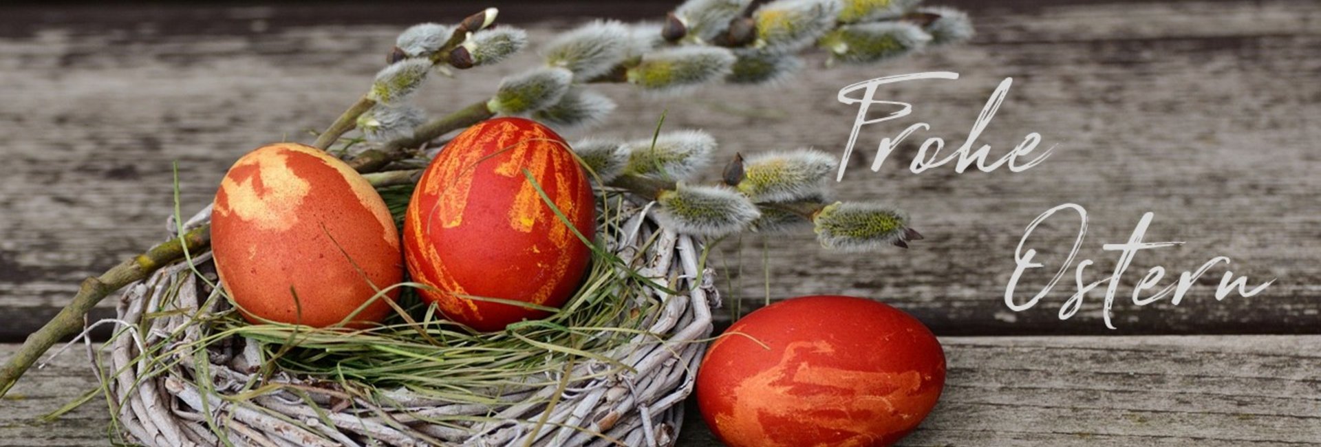 zwei rote Eier im Nest, ein rotes liegt daneben, mit Beschriftung Frohe Ostern