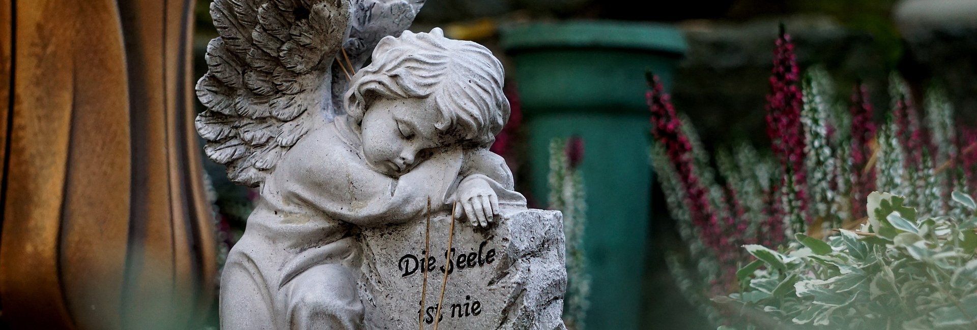 Ein Engel stützt sich auf einen Stein, mit der Aufschrift "Die Seele ist nie ohne Geleit"