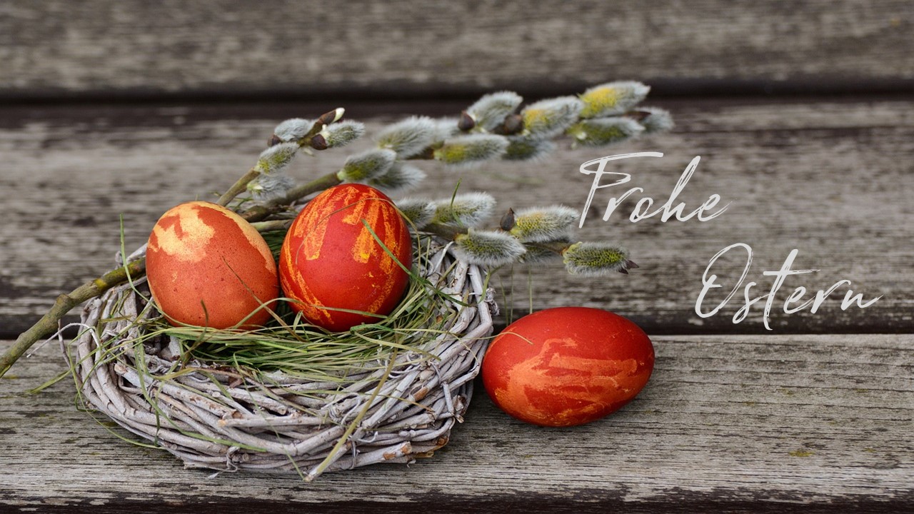 zwei rote Eier im Nest, ein rotes liegt daneben, mit Beschriftung Frohe Ostern