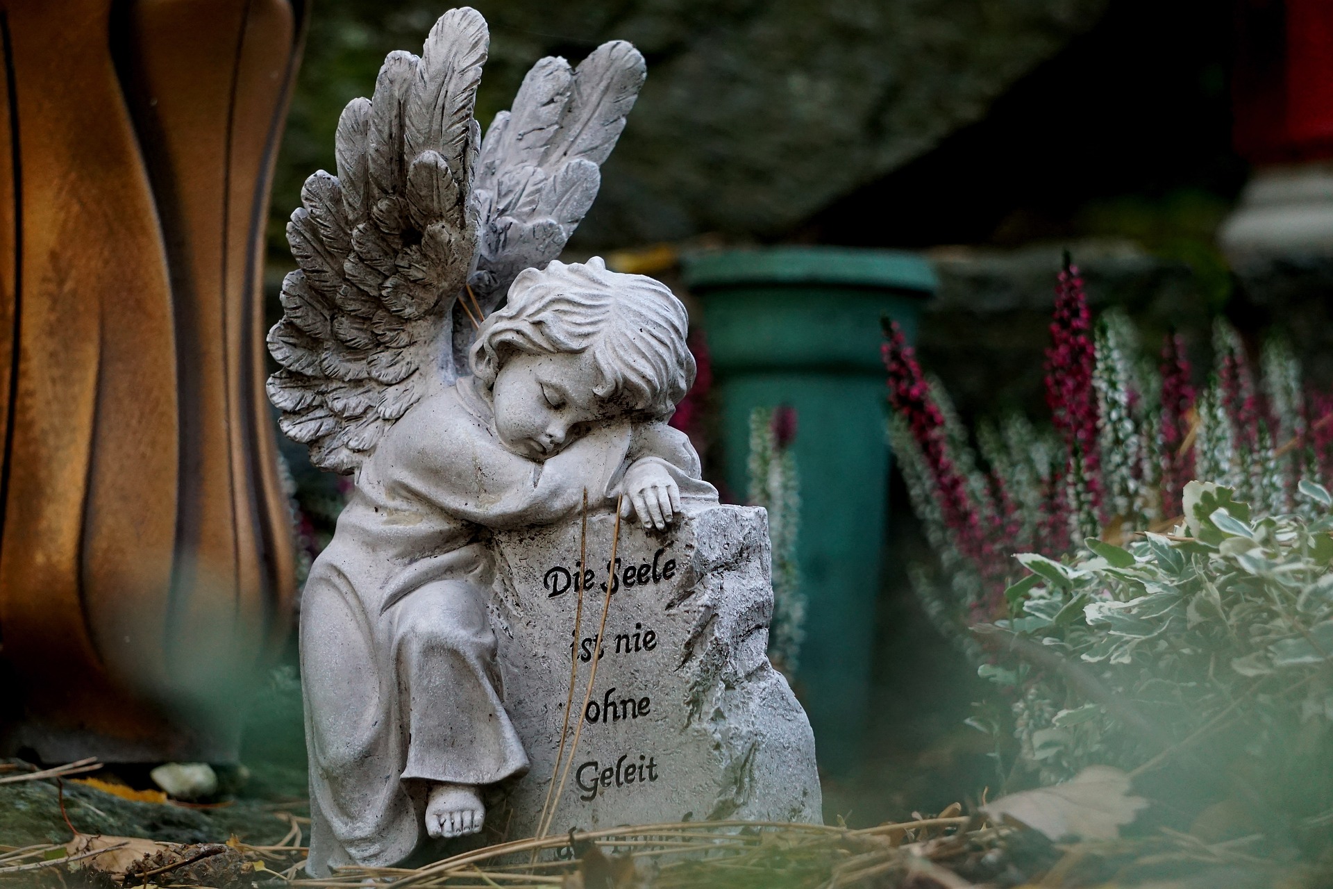 Ein Engel stützt sich auf einen Stein, mit der Aufschrift "Die Seele ist nie ohne Geleit"